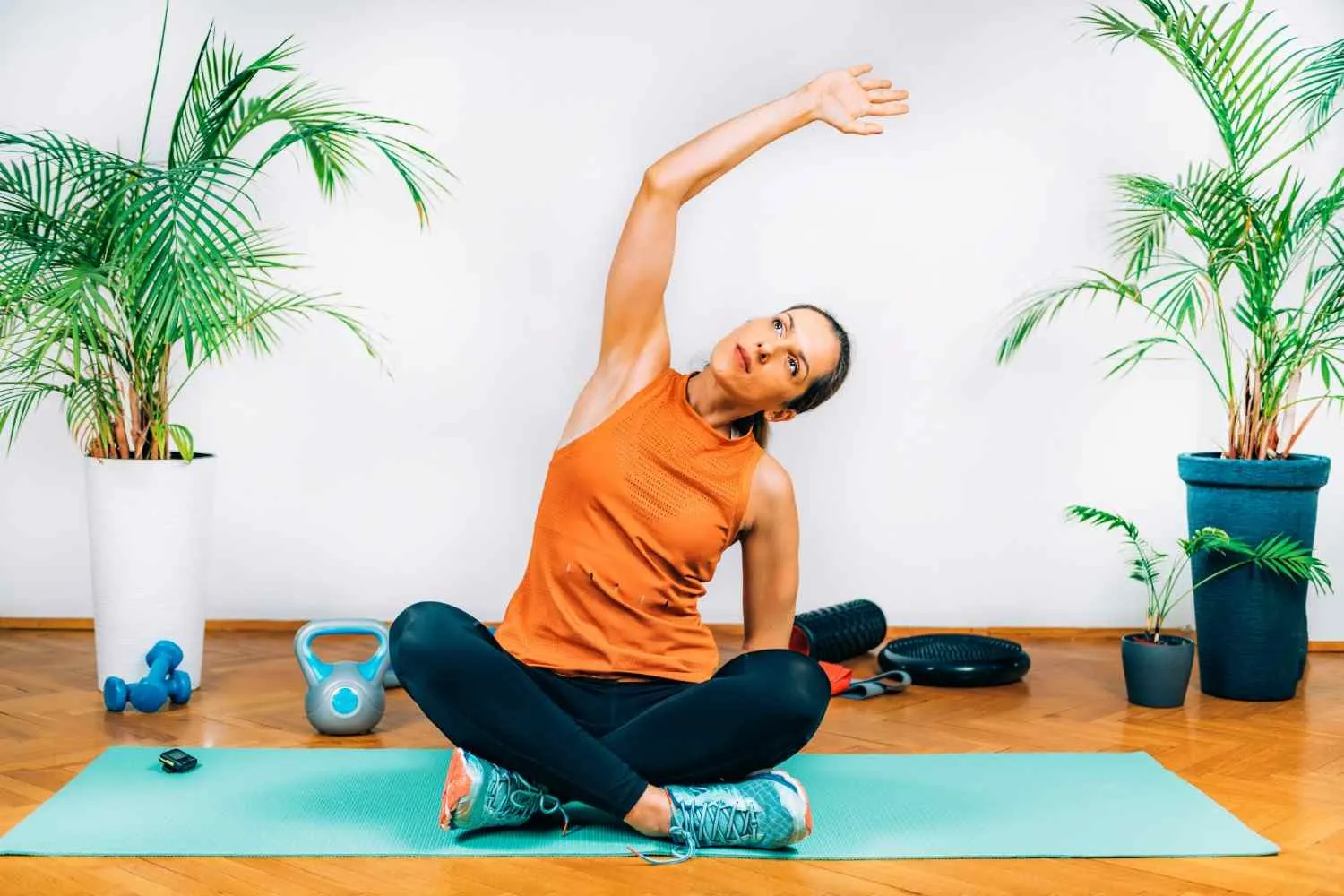 Woman stretching to one side while sitting cross legged on a yoga mat