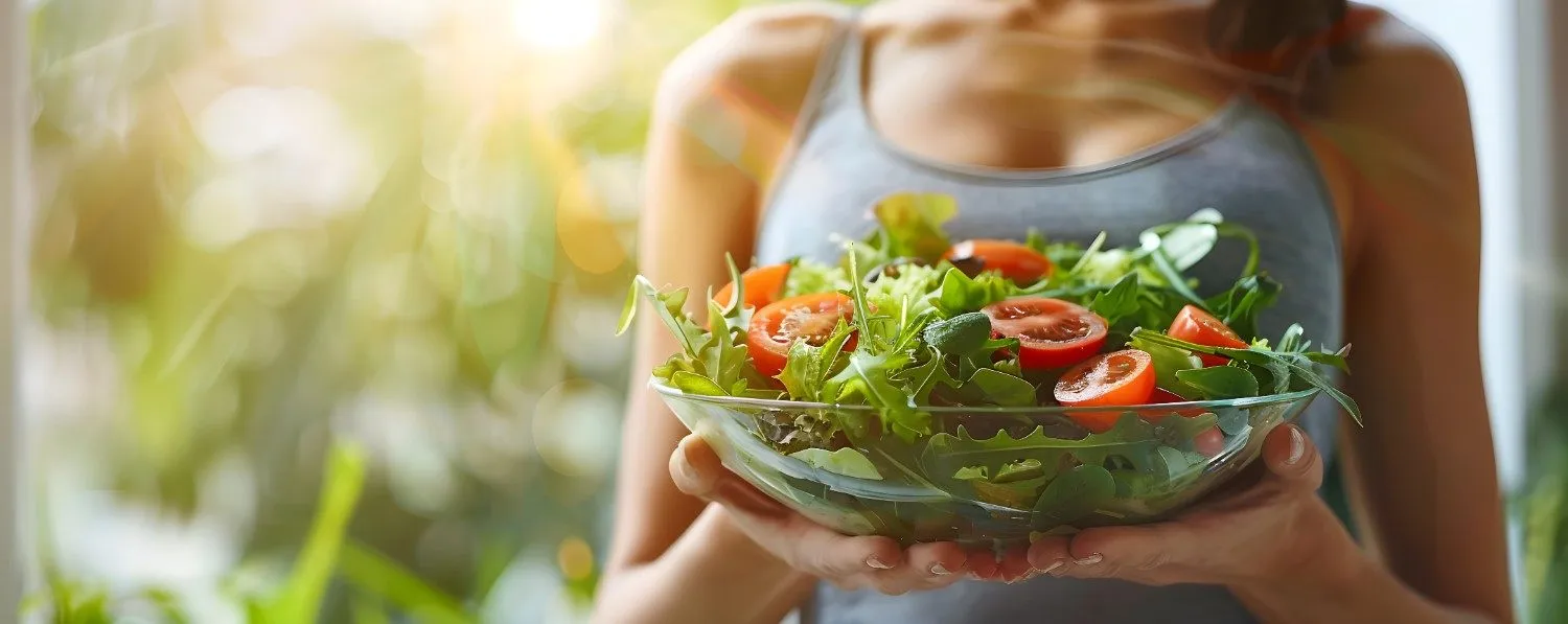Woman holding a large bowl of fresh salad outdoors
